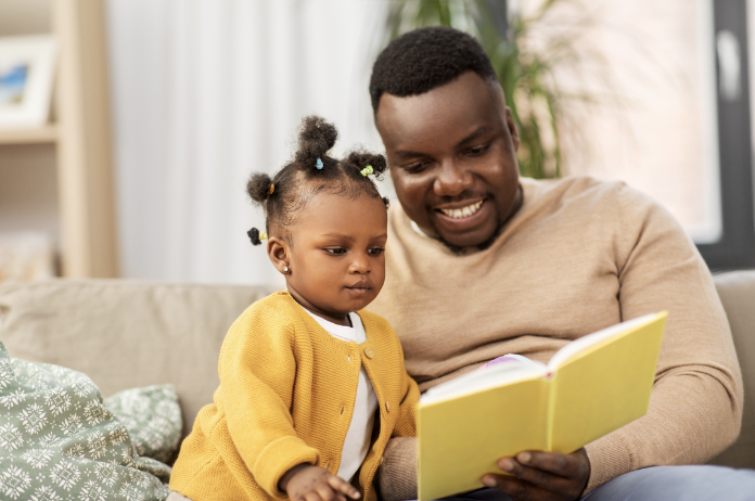 A parent reads to their toddler who intently studies the page.